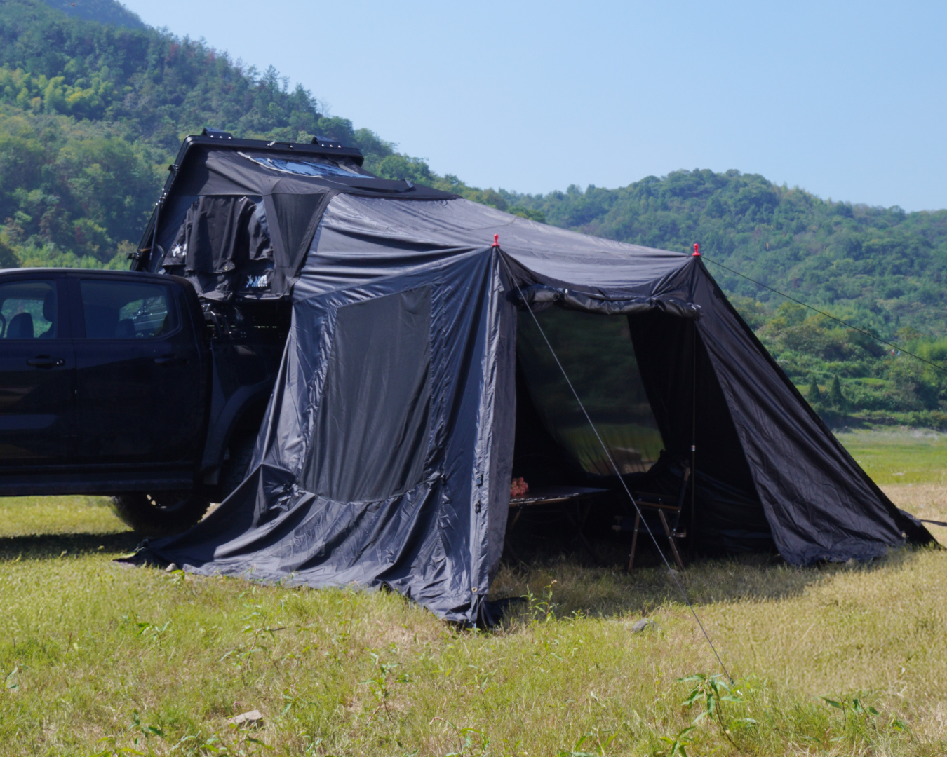 Vorzelt für das NUCIS Dachzelt von ARCTA, aufgebaut in einer grünen Landschaft, ideal für Camping und Outdoor-Abenteuer.