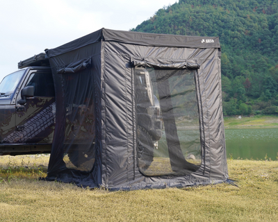 Vorraum für Shade PRO, mit Netzfenstern für Belüftung, aufgestellt neben einem Fahrzeug in einer grünen Landschaft.